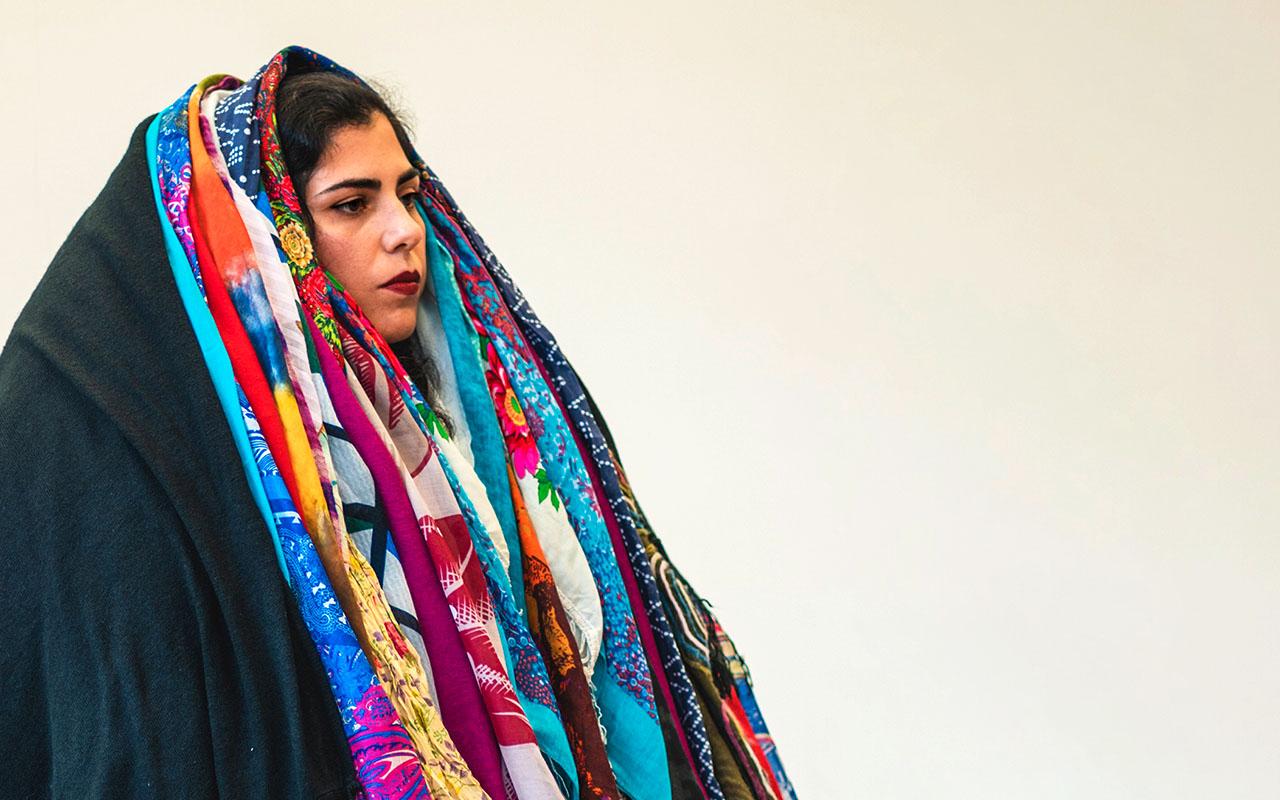 Farzane Vaziritabar, eine iranische Künstlerin ist im Rahmen ihrer Performance mit vielen bunten Tüchern behangen.
