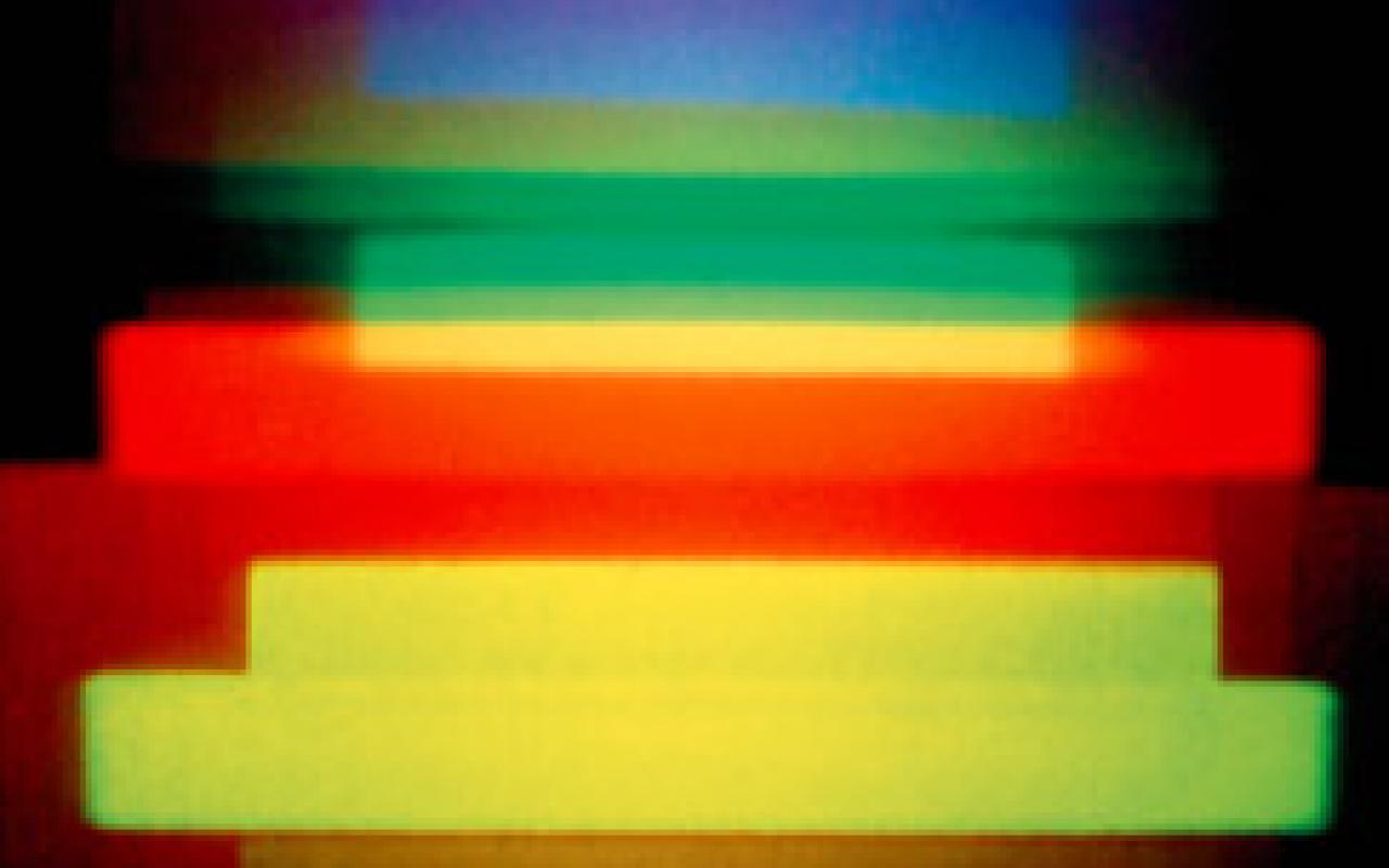 A holographic image by Dieter Jung. Red, blue, green and yellow horizontal stripes on a dark background.