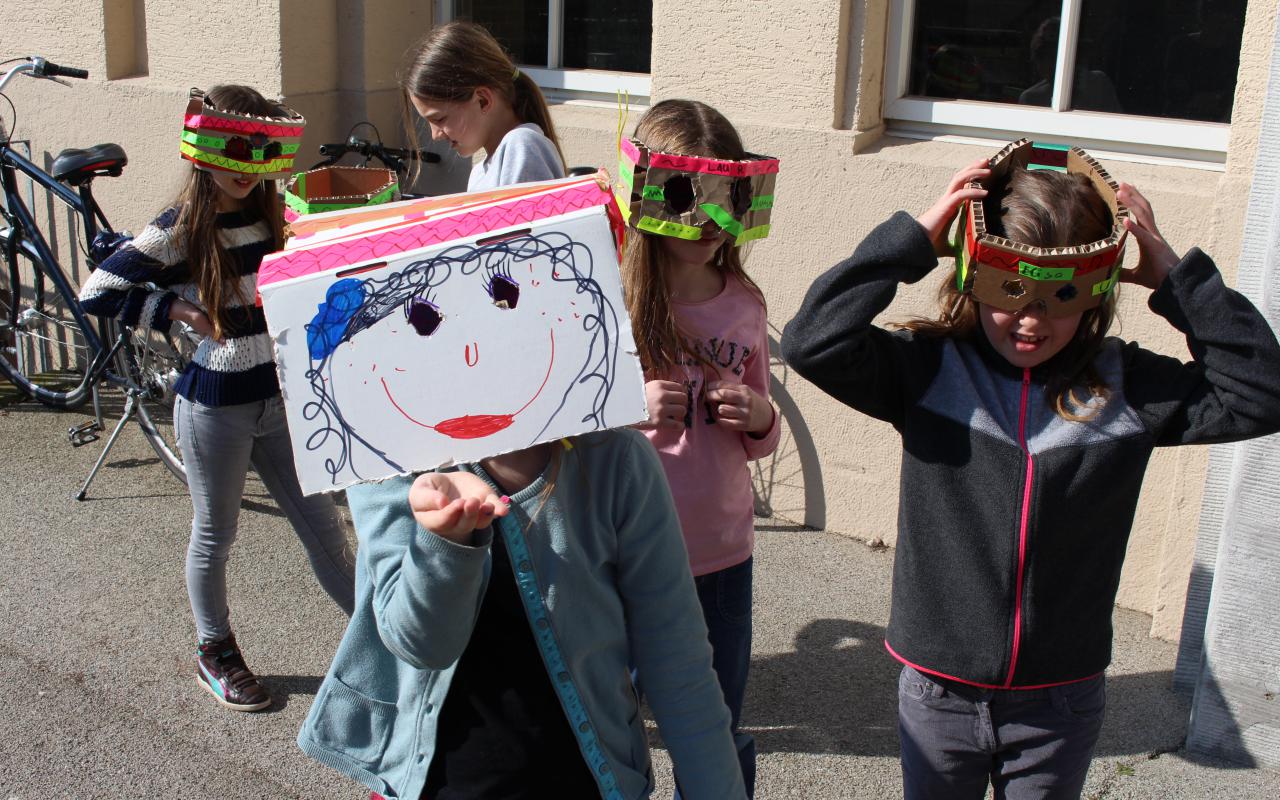 Eine Gruppe Mädchen, die sich aus alltäglichen Gegenständen Masken gebastelt haben stehen vor dem Eingang zum ZKM Gebäude.