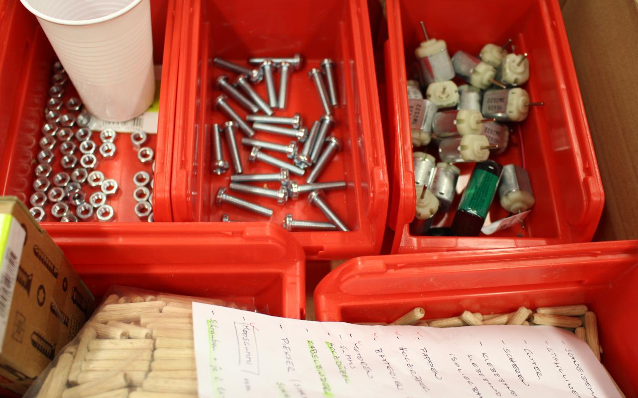Some red boxes for crafting equipment in which are different screws, nails or little motors.
