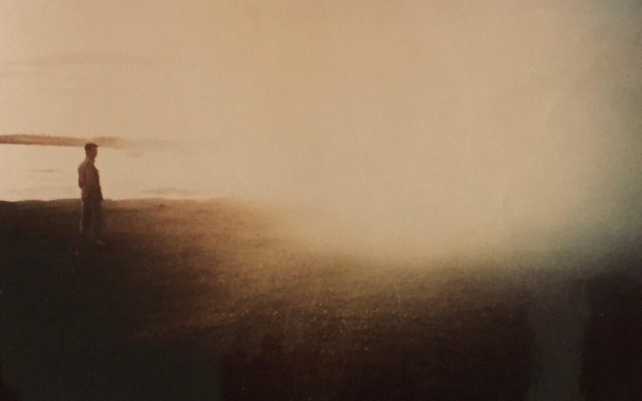 On the left side there is a man standing in front of a sea. On the right, the image is heavily overexposed.