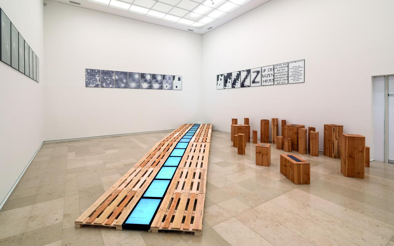 Monochrome screens lie in the middle of a longer row of palettes. On the right are single small blocks. On the walls hang small square posters with abstract motives.