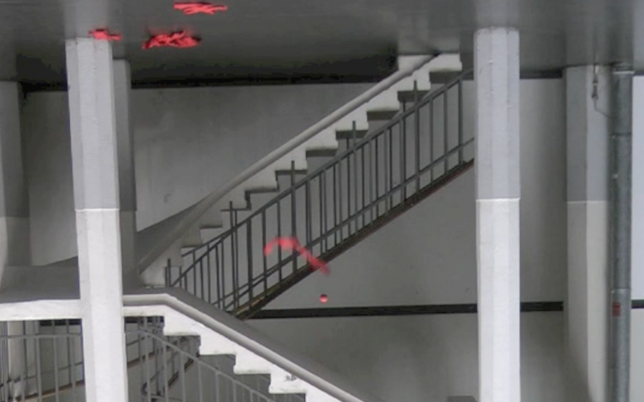 Ein Treppenhaus ist verkehrt herum zu sehen, ein roter Stoffstreifen und ein Ball scheinen nach oben zu fallen.