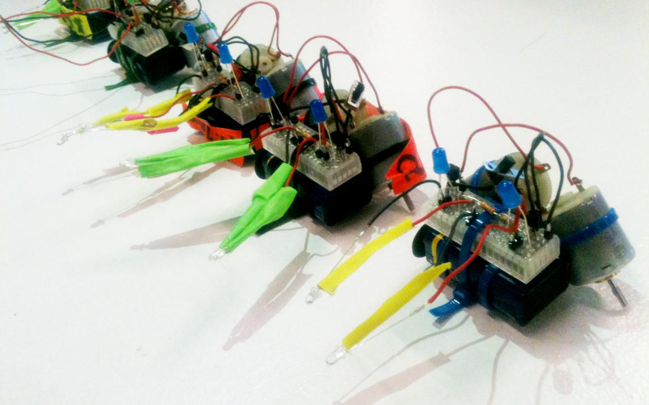 Fünf kleine T2-R2-Roboter aus verschienen elektronischen Teilen und durch Kabelbinder zusammengehalten.