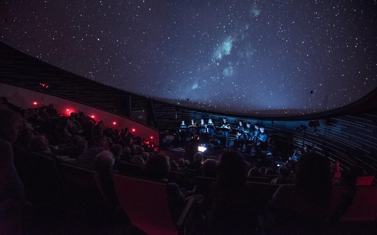 Das KlangForum auf der Bühne vor einem projizierten Sternenhimmel