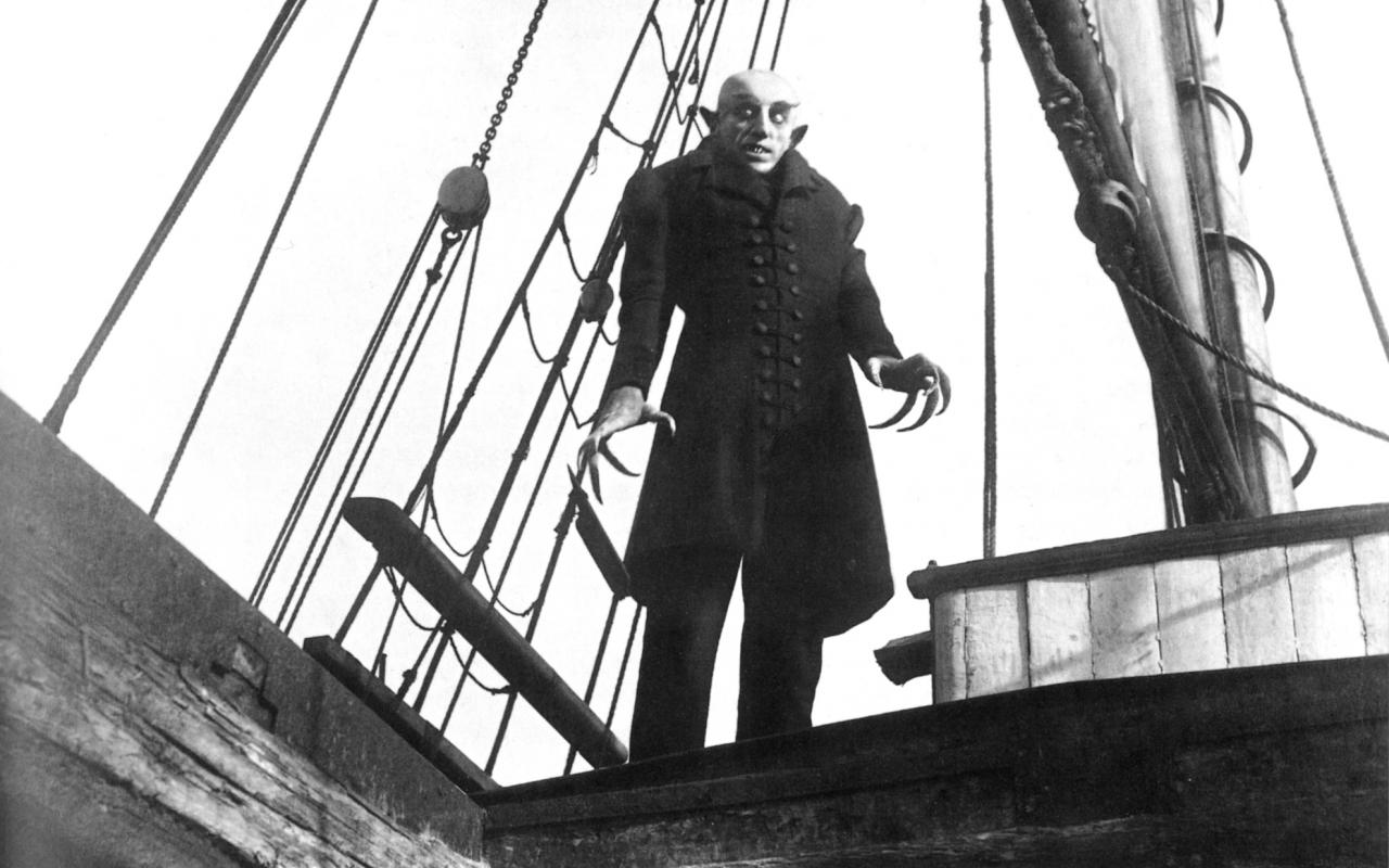A man with claw hands is standing on a boat
