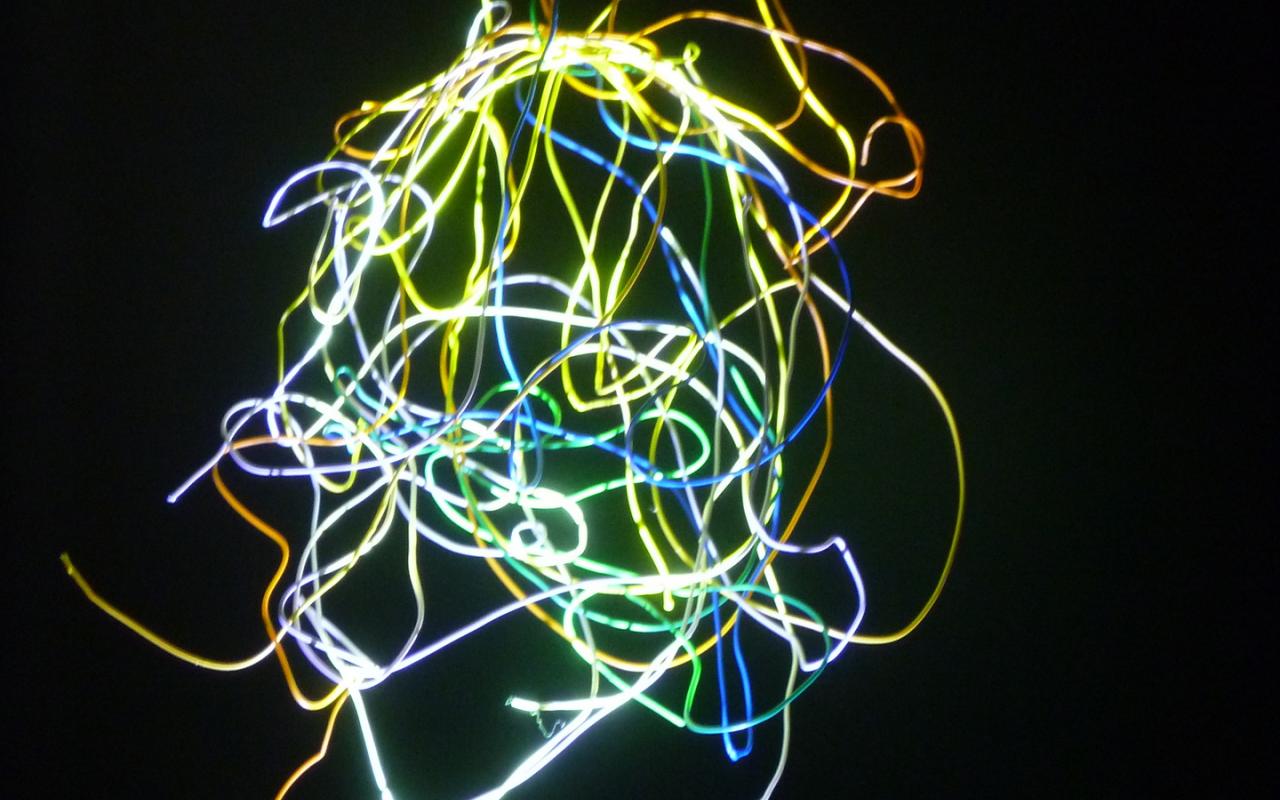 Man sieht das Werk »Pneuma 4«. Mehrere geschwungene Linien, die in verschiedenen Farben leuchten, sind miteinander verwoben.