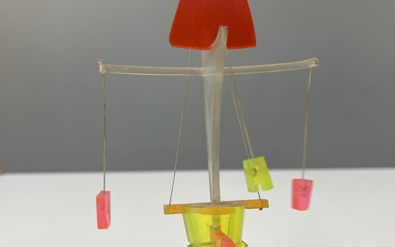Figures for »Tanz im Labyrinth« by Otto Beckmann. ou can see a small sculpture that resembles a carousel. The apex is a red triangle. Red and yellow blocks are hanging from the threads.