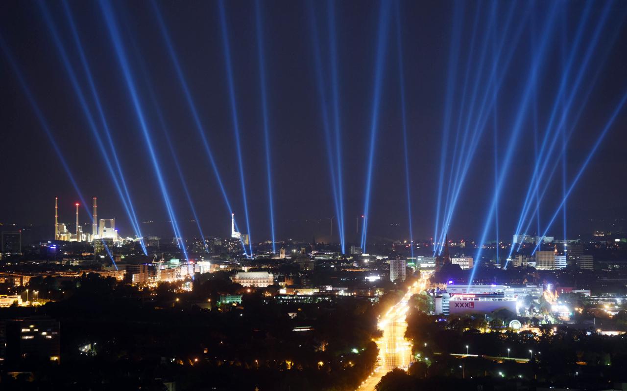 The city of Karlsruhe on a photo at night, in the sky bright rays can be seen, the buildings of the city are illuminated.