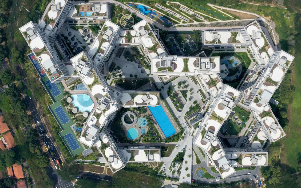 The photo shows a large building complex from a bird's eye view. From above you can see how the floors are built on top of each other and in between you can see a lot of greenery and pools.