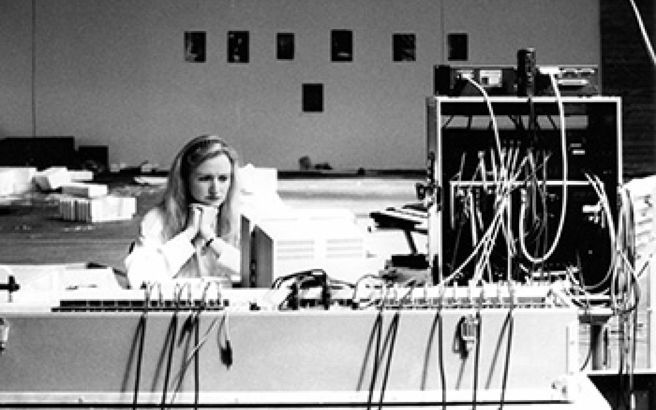 Black and white photo of Sabine Schäfer, she sits lost in thought at the console.