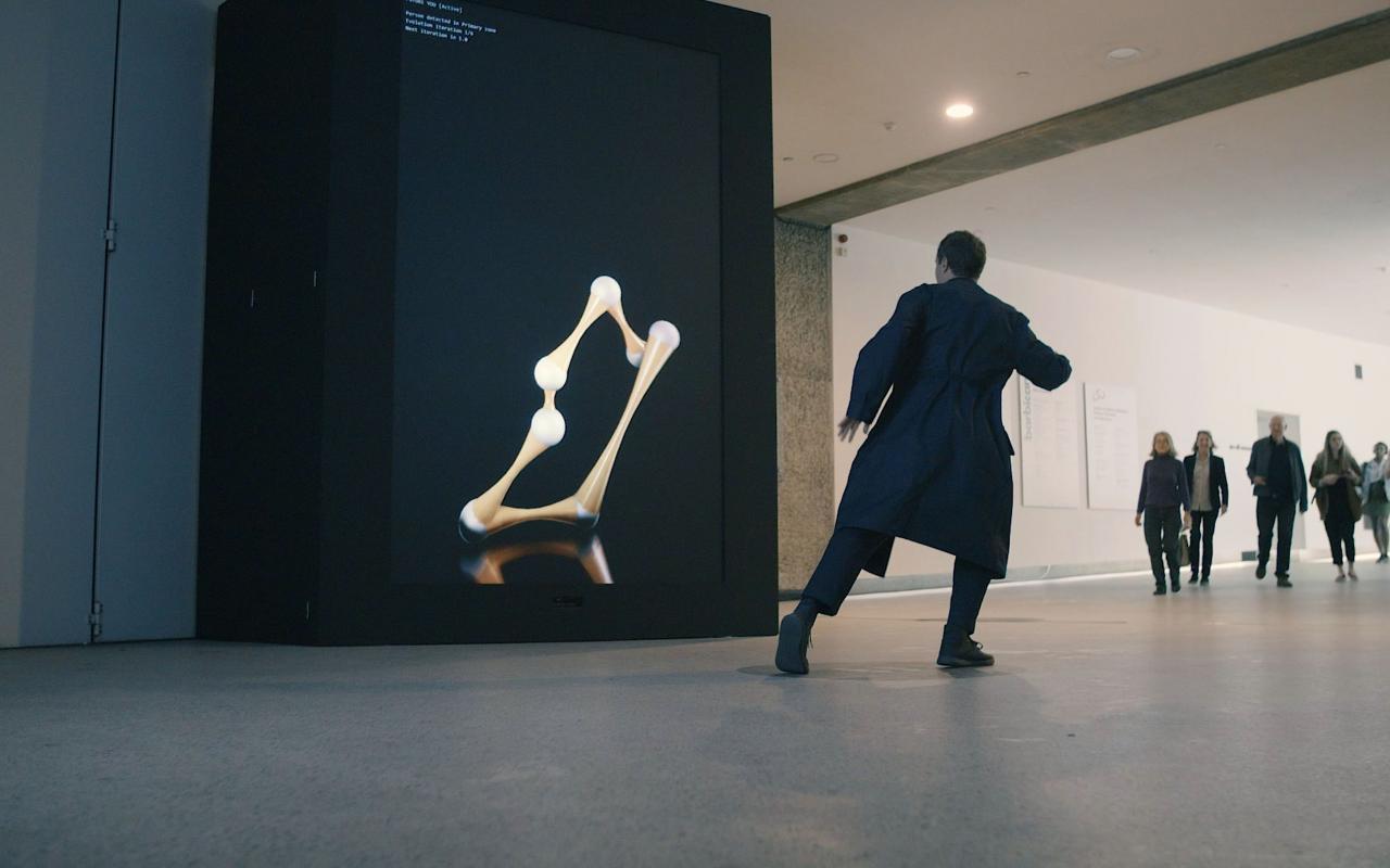 Zu sehen ist ein Mann, der sich vor einem Kunstwerk bewegt, mit ihm interagiert 