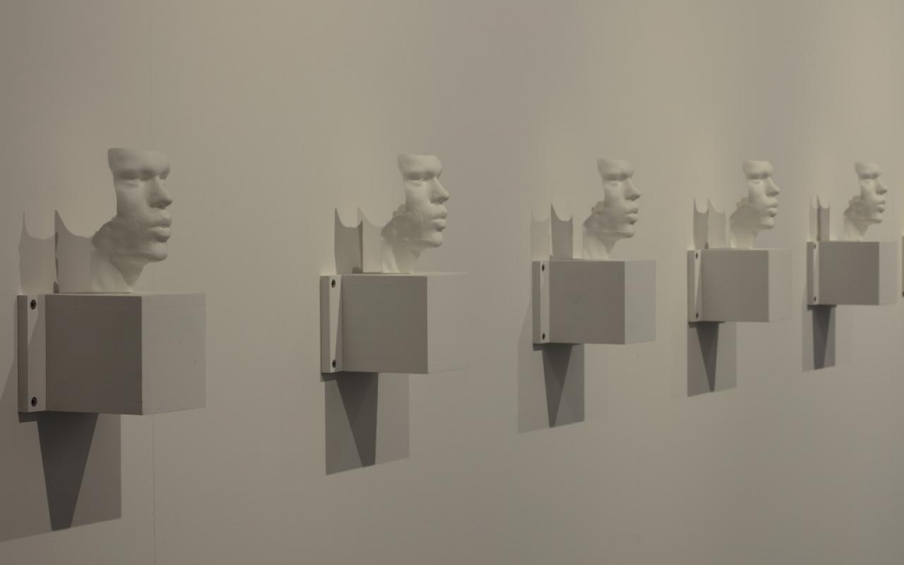  Several busts - 3D prints of the artists' vocal bands - hang side by side on a wall.