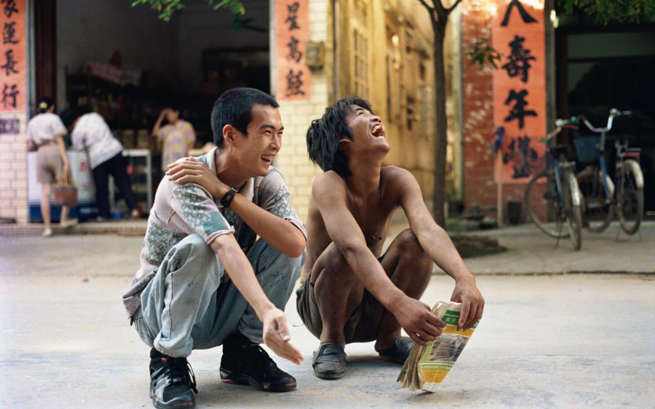 Zwei kauernde und lachende Männer in China 