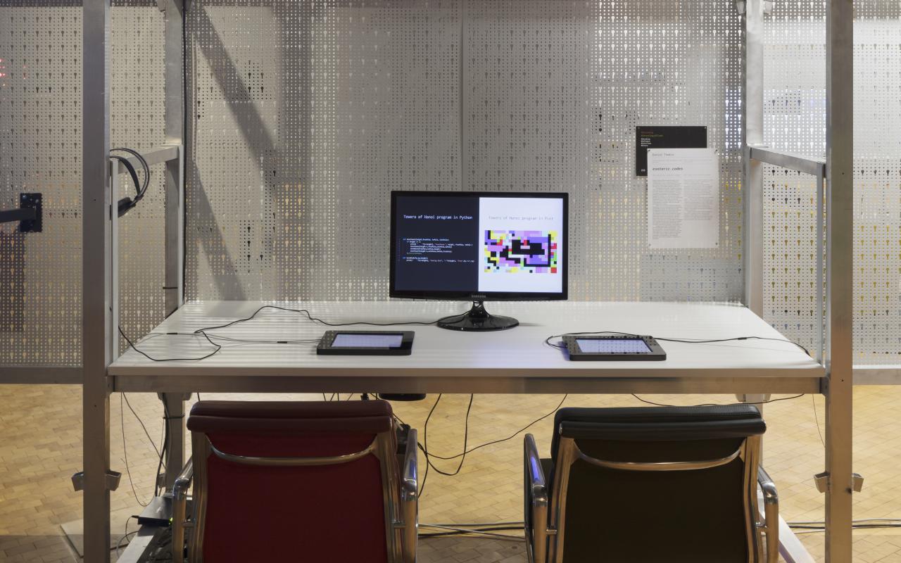 Ein Schreibtisch mit Monitor und zwei Stühlen