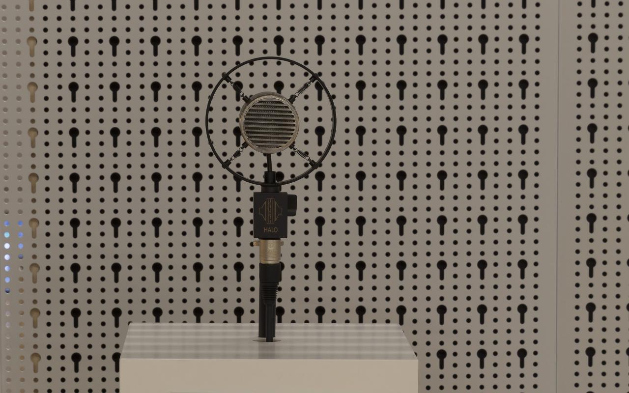 An old carbon microphone on a white pedestal.