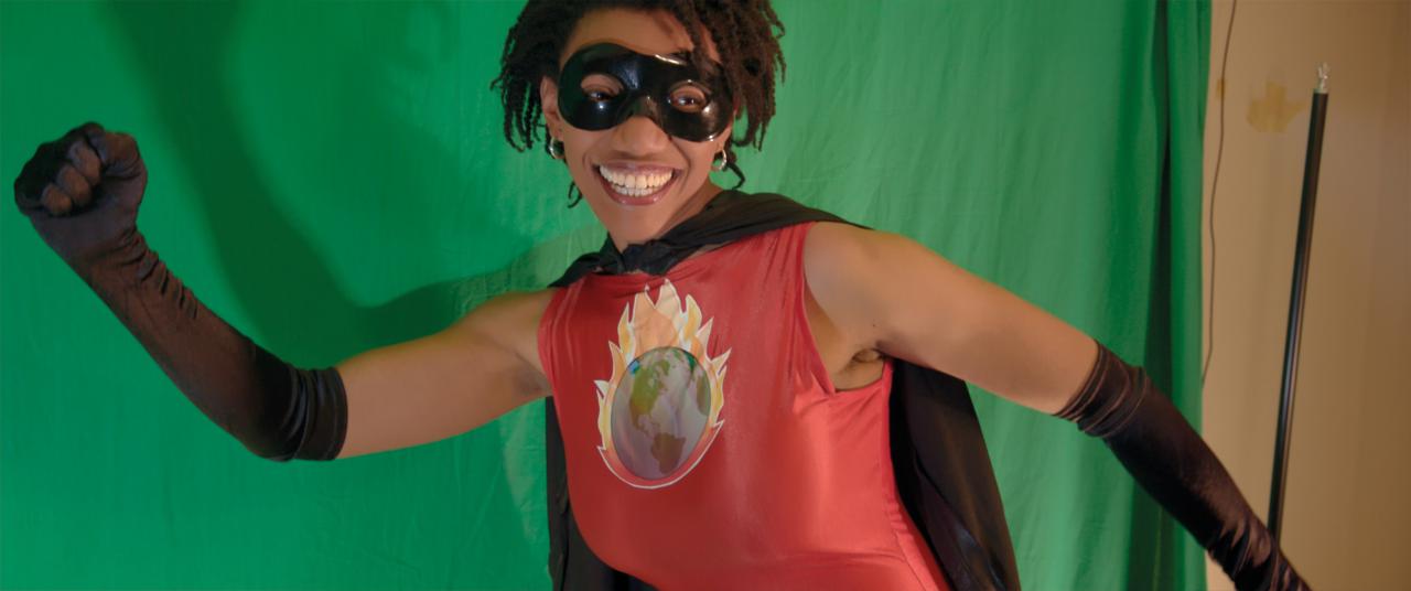 A woman is wearing a superhero costume, smiles and raises her right fist
