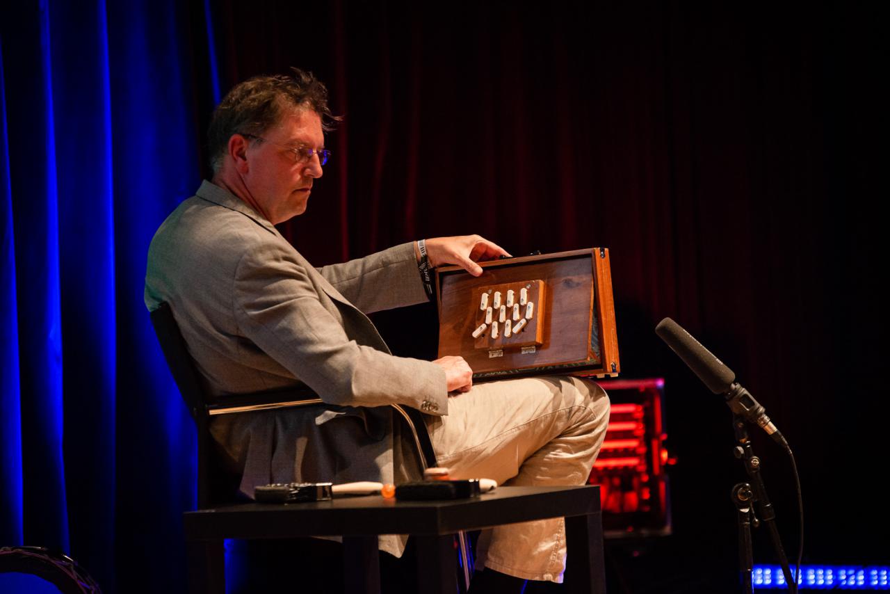 Manos Tsangaris creates sounds on a curious wooden instrument that resembles a combination of box and accordion.