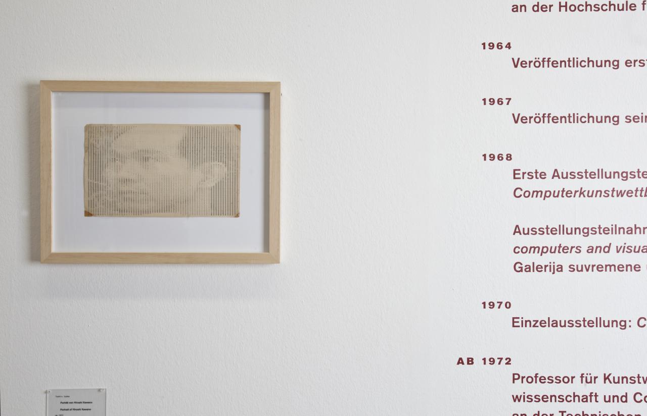 Blick auf eine weiße Wand: Links ein Portrait von Hiroshi Kawano, rechts sein Lebenslauf.
