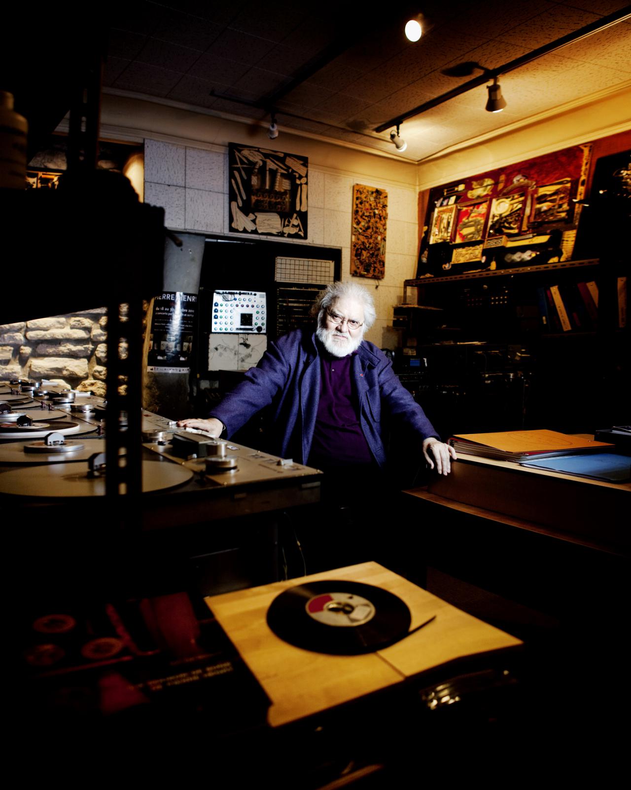 A man sits amid several turntables