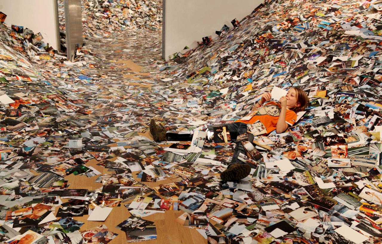 A boy lying in a pile of photographs