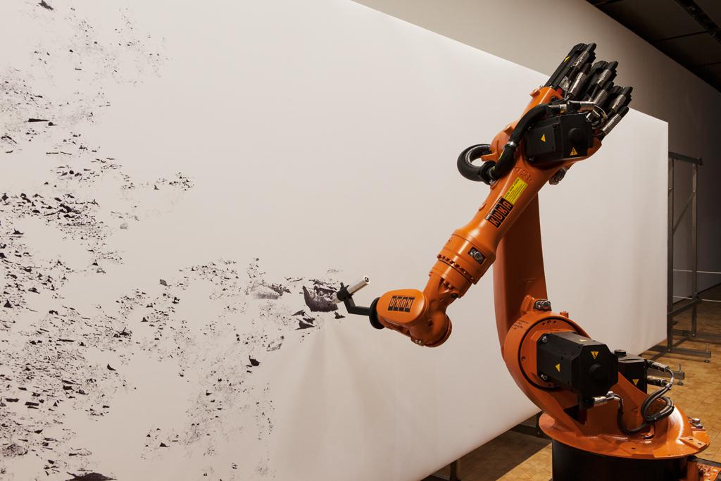 Ein Industrieroboter zeichnet ein mit einem Stift auf ein Großformat