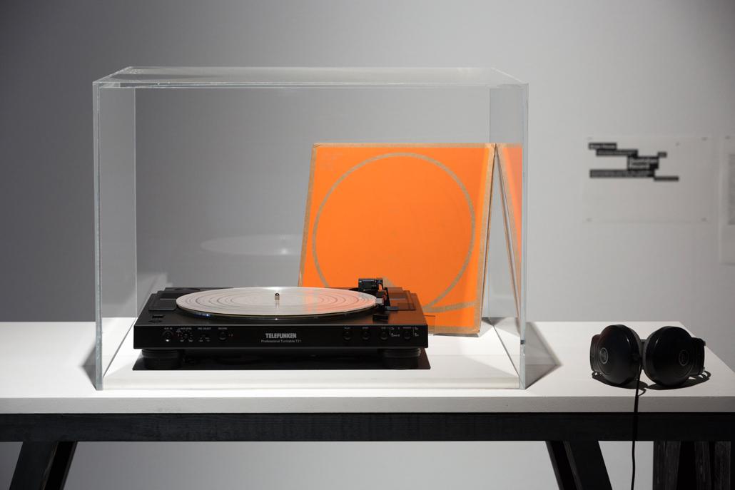 An old record player and an orange disk cartridge in a showcase