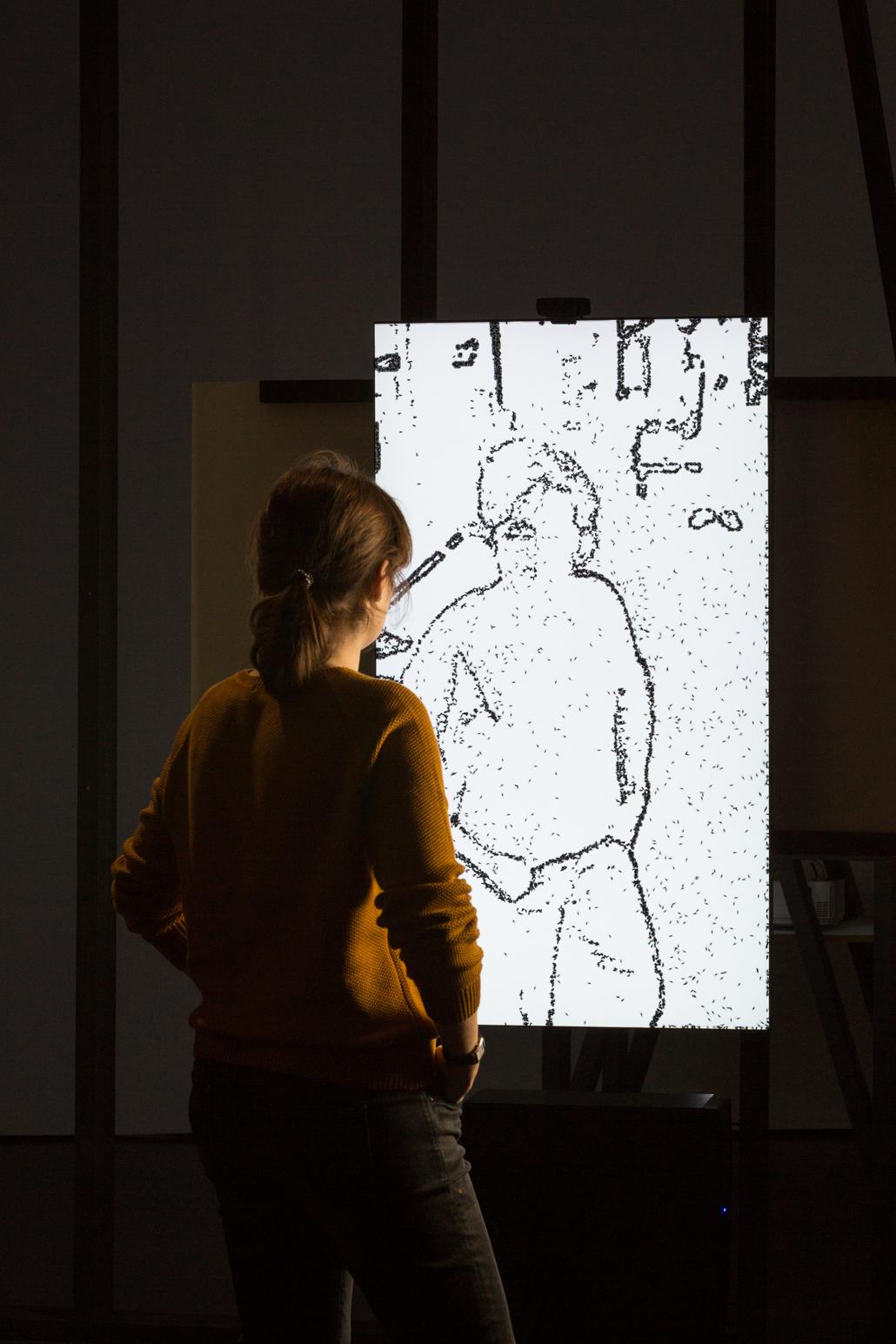 A person stands in front of a drawing of a person