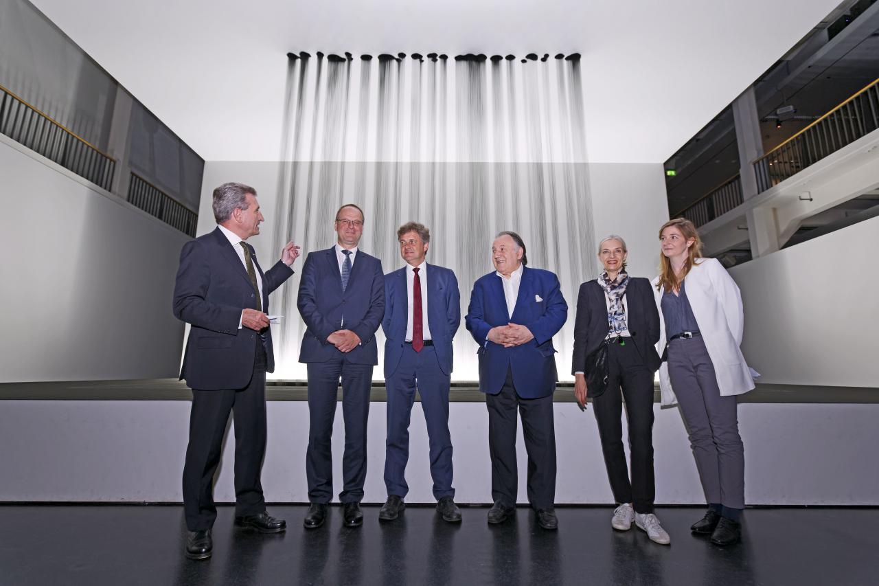 Four men and two women standing in front of an installation that represents a kind of curtain of oil.