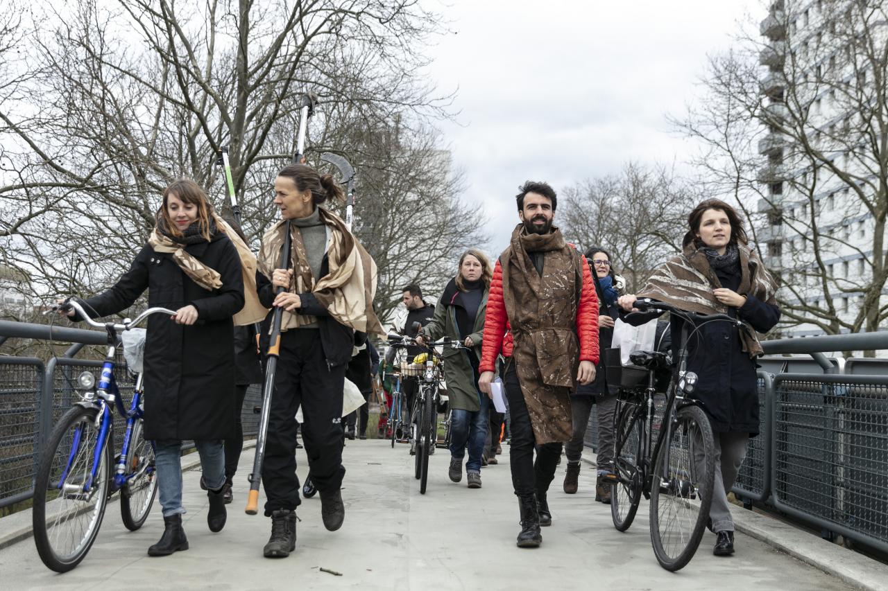 Eine Gruppe von Menschen gehen in einer Prozession mit Fahrrädern.