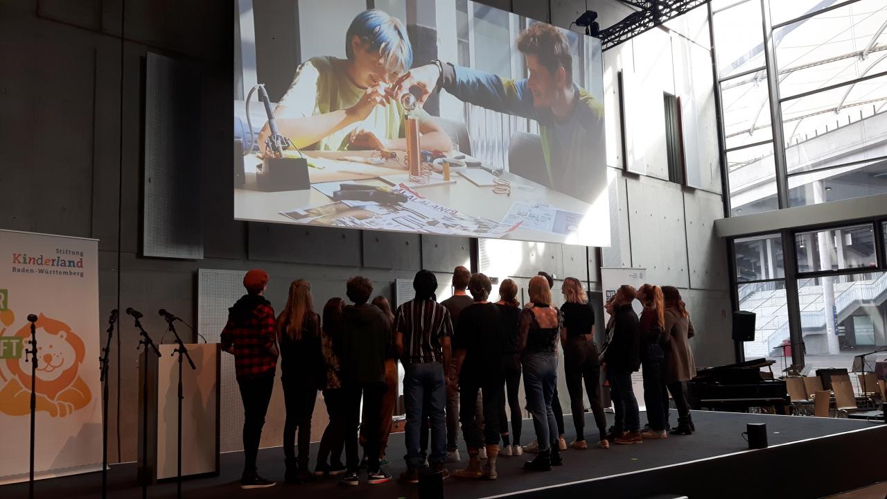 A group of students stand under a projection as part of the »Cultural Academy« project at ZKM.
