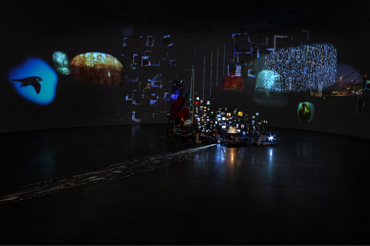 Photo of a dark exhibition room with luminous reflections.