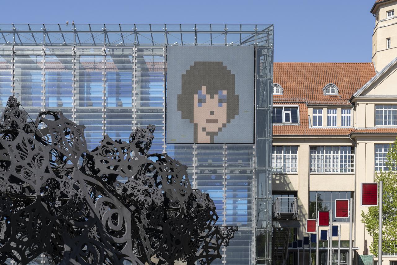 Crypto art: an illustrated face in pixel style on the LED wall of the ZKM Cube