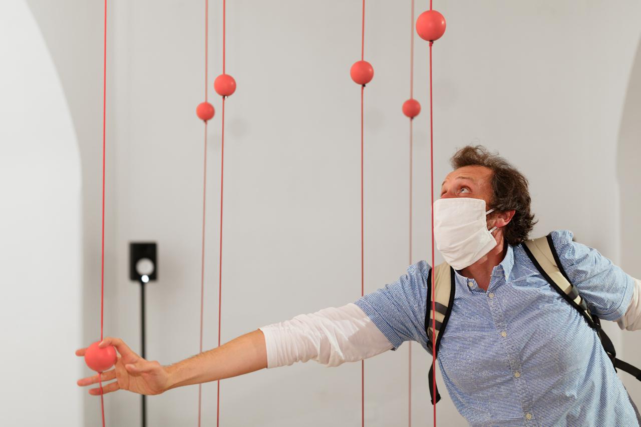 A man touches a ball attached to a rope stretched between the ceiling and the floor.