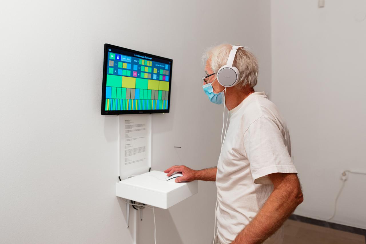 A man stands in front of a screen and controls it with a computer mouse.