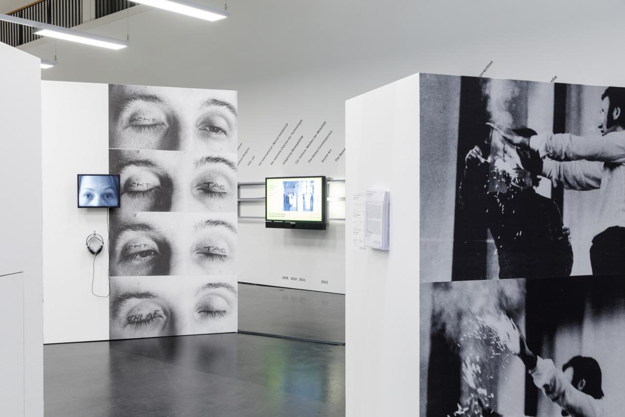 In the middle two movable walls, on the right wall a screen and text. On the movable wall, at the left, a small screen with headphones and printed large photos of eyes, on whose lids "day", "night" or "sleep" are written.