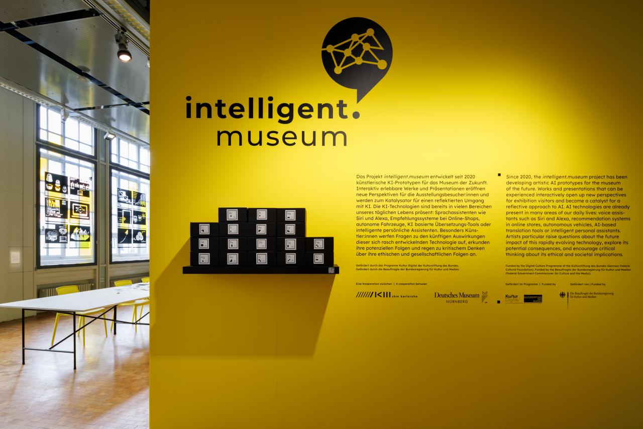 Zu sehen ist eine gelbe Wand mit dem Logo intelligent.museum und einem Einführungstext.
