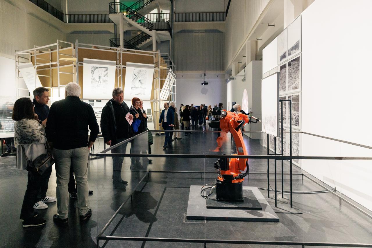 Zu sehen ist ein orangefarbener Roboter in der Ausstellungsfläche Renaissance 3.0.