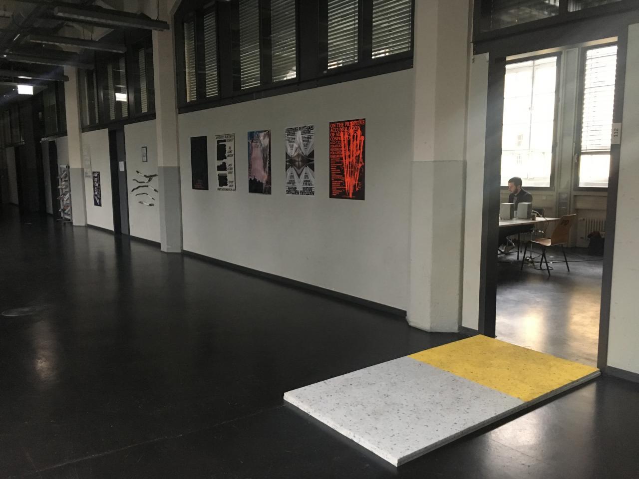 Vor dem Eingang des Seminarraumes des Critical Zones Forschungsseminars an der Staatlichen Hochschule für Gestaltung Karlsruhe (HfG) befindet sich eine Schaumstoffmappe auf dem Boden als Test für alle SeminarteilnehmerInnen.