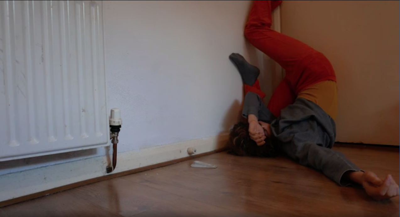 The image shows a person lying on the floor and moving along the wall with his legs.