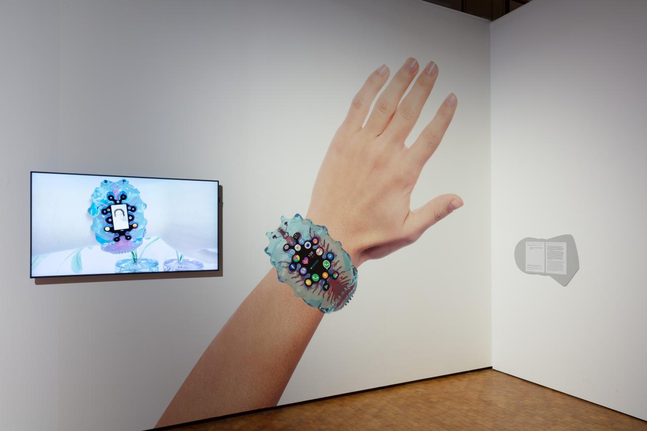 Aristarkh Chernyshev, »Personal information Organism. PiO ver 1.0«, 2019. Auf dem Bild ist eine Hand zusehen, die eine Uhr trägt. Diese Uhr ist eine Mischung aus einem genetisch veränderten Blutegel und einem Mobiltelefon.