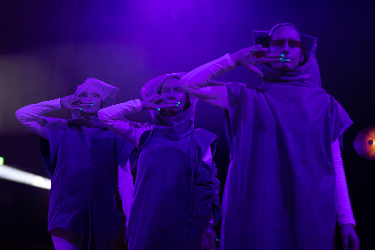 You can see three people, standing next to each other, wrapped in purple light