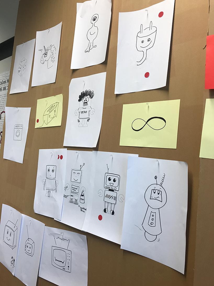 Zeichnungen mit möglichen Chatbot-Charakteren auf einer Pinnwand.