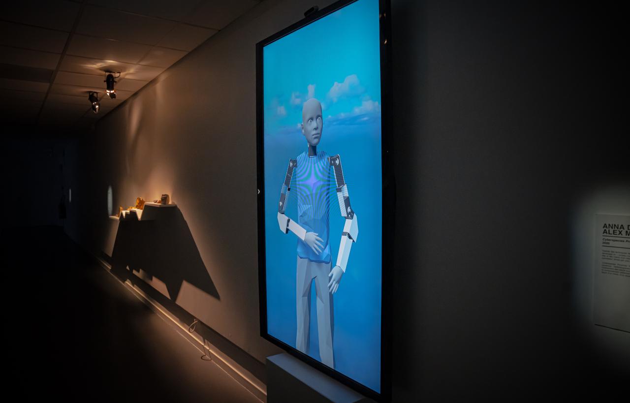 Zu sehen ist ein humanoider digitaler Roboter auf einem Bildschirm vor einem blauen Hintergrund.