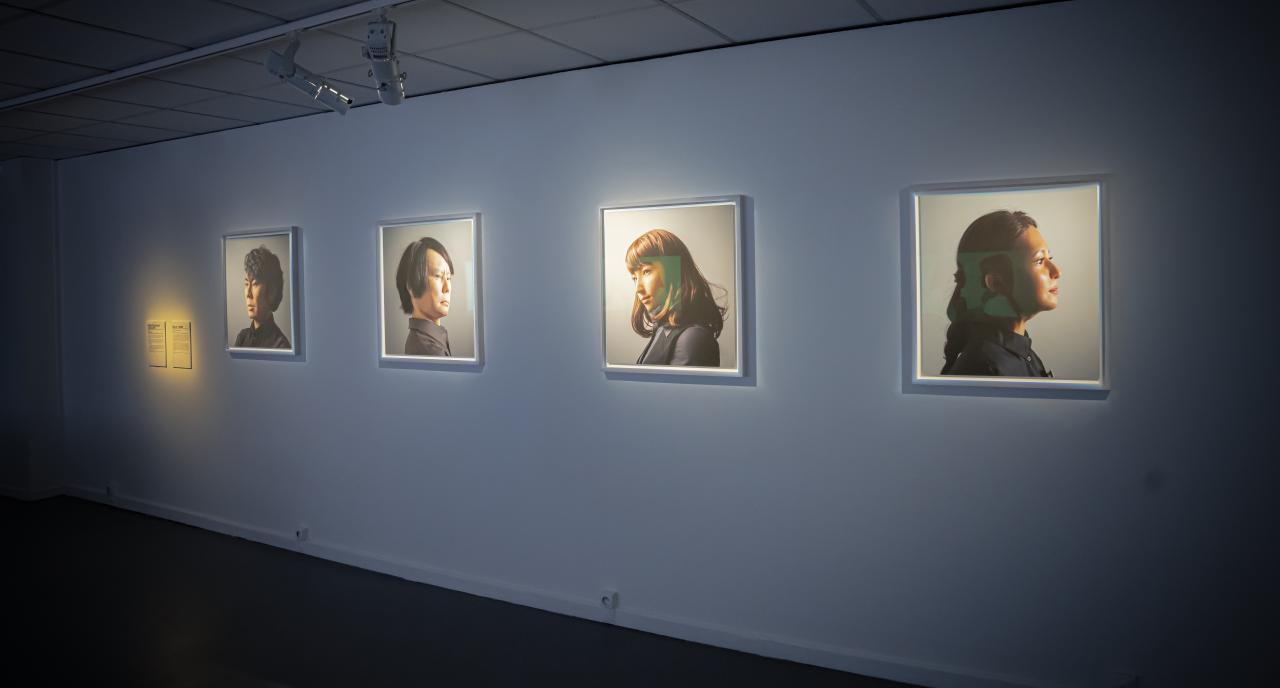 Maija Tammi, »One of Them Is a Human, #1-4«, 2017. Zu sehen sind vier Porträts, die unterschiedliche Menschen abbilden, an einer Wand. 