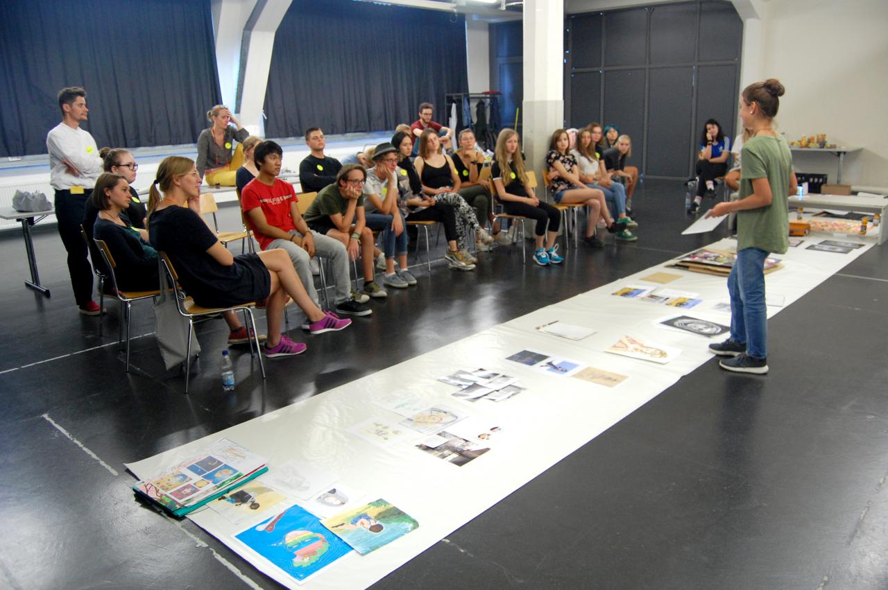Eine Schülerin stellt einer Gruppe von Schülern verschiedene Bildwerke vor im Rahmen einer Veranstaltung der Kulturakademie.