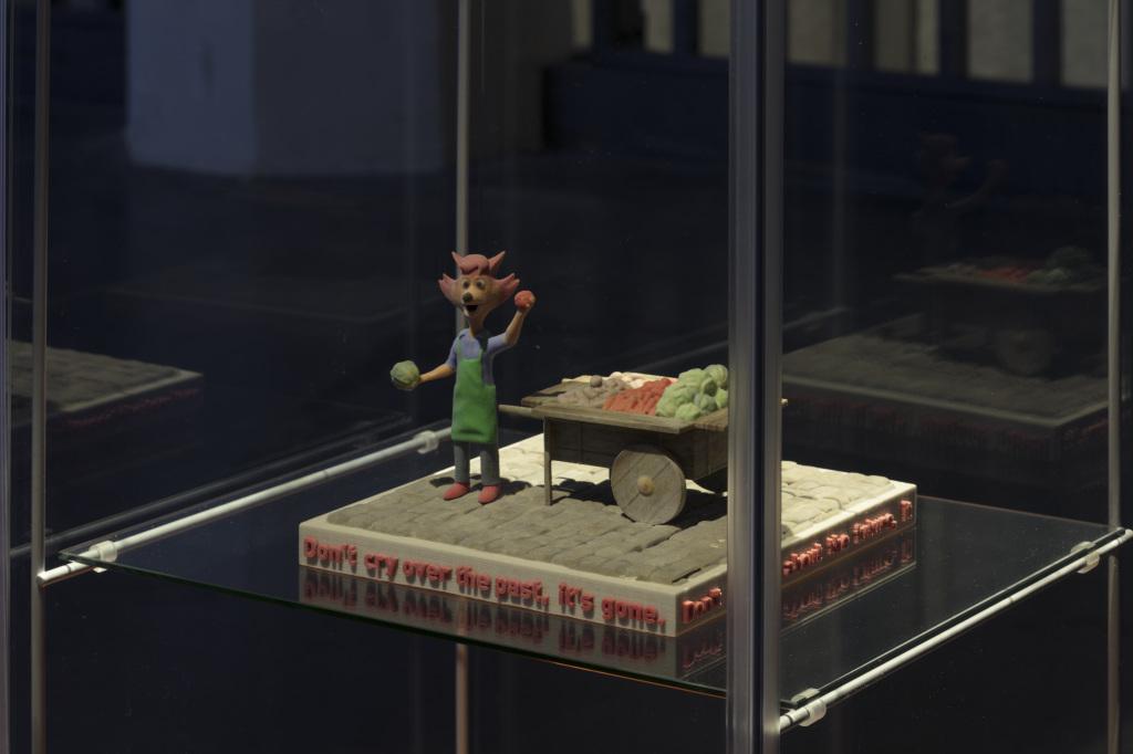  A small kneaded fox stands on a pedestal in a display case