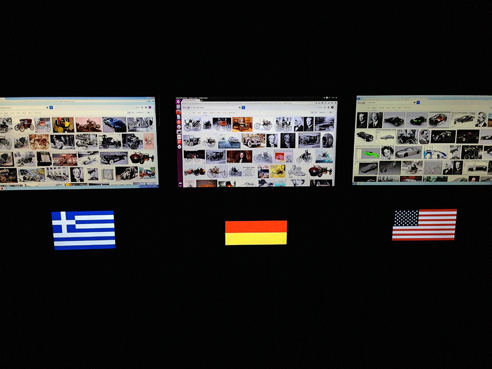 Three screens with diverse content; below the flags of Greece, Germany and the US
