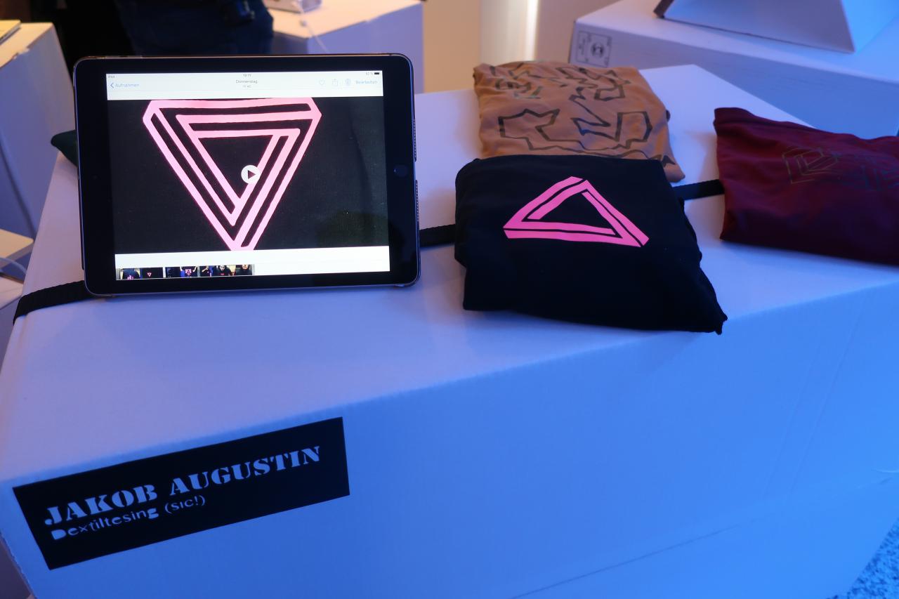 Zu sehen ist ein Ipad und T-Shirts auf einem Tisch im Rahmen einer Veranstaltung der Kulturakademie.