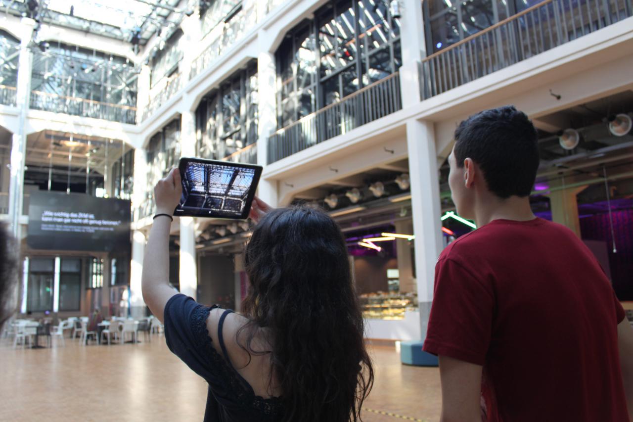 Two students taking a photo of the ceiling of the ZKM with an iPad as part of the event »Global Sound«. 